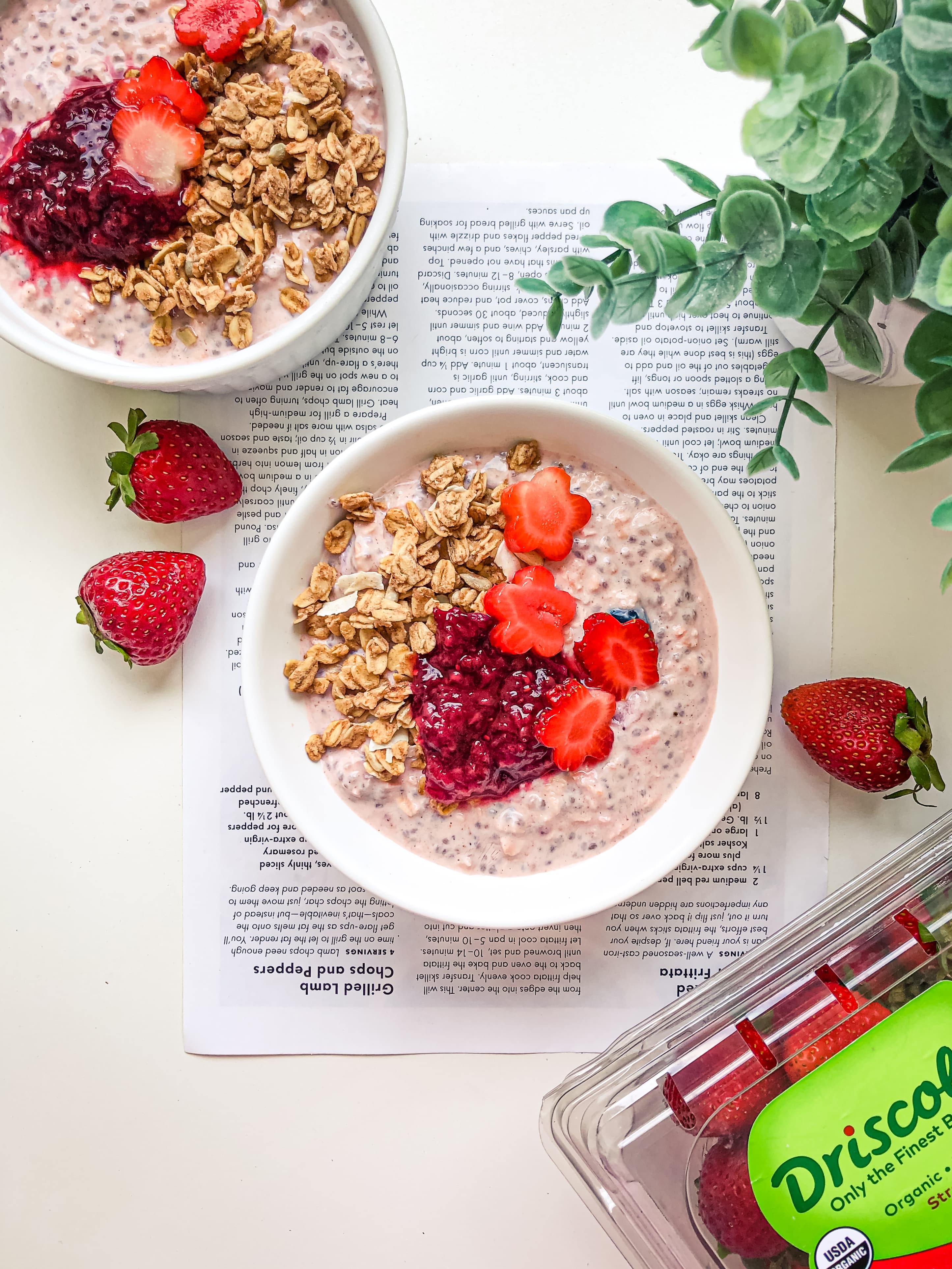 Strawberry shortcake overnight oats topped with granola, berry sauce, and flower-shaped strawberry slices