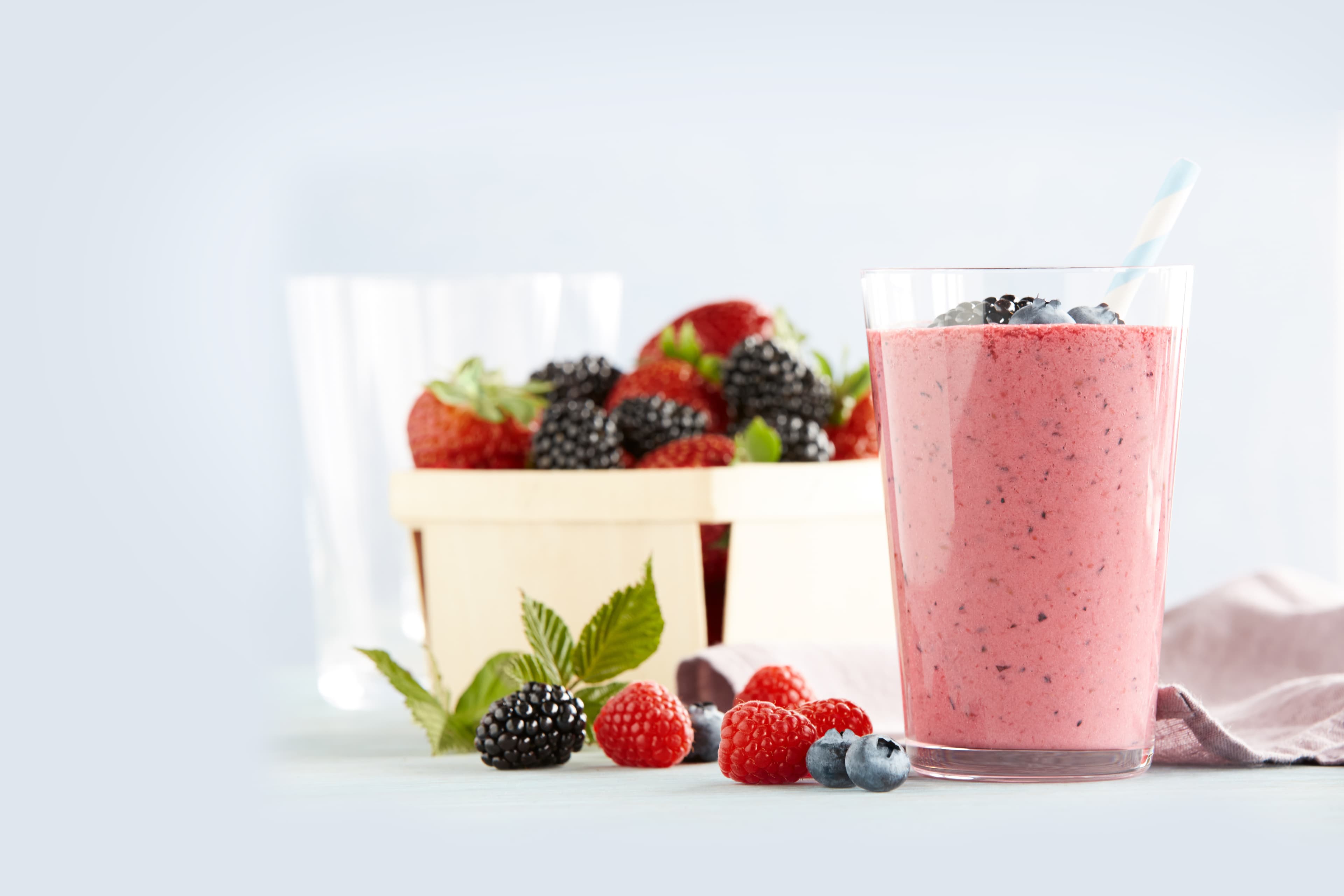 Glass of a berry smoothie and a basket of berries
