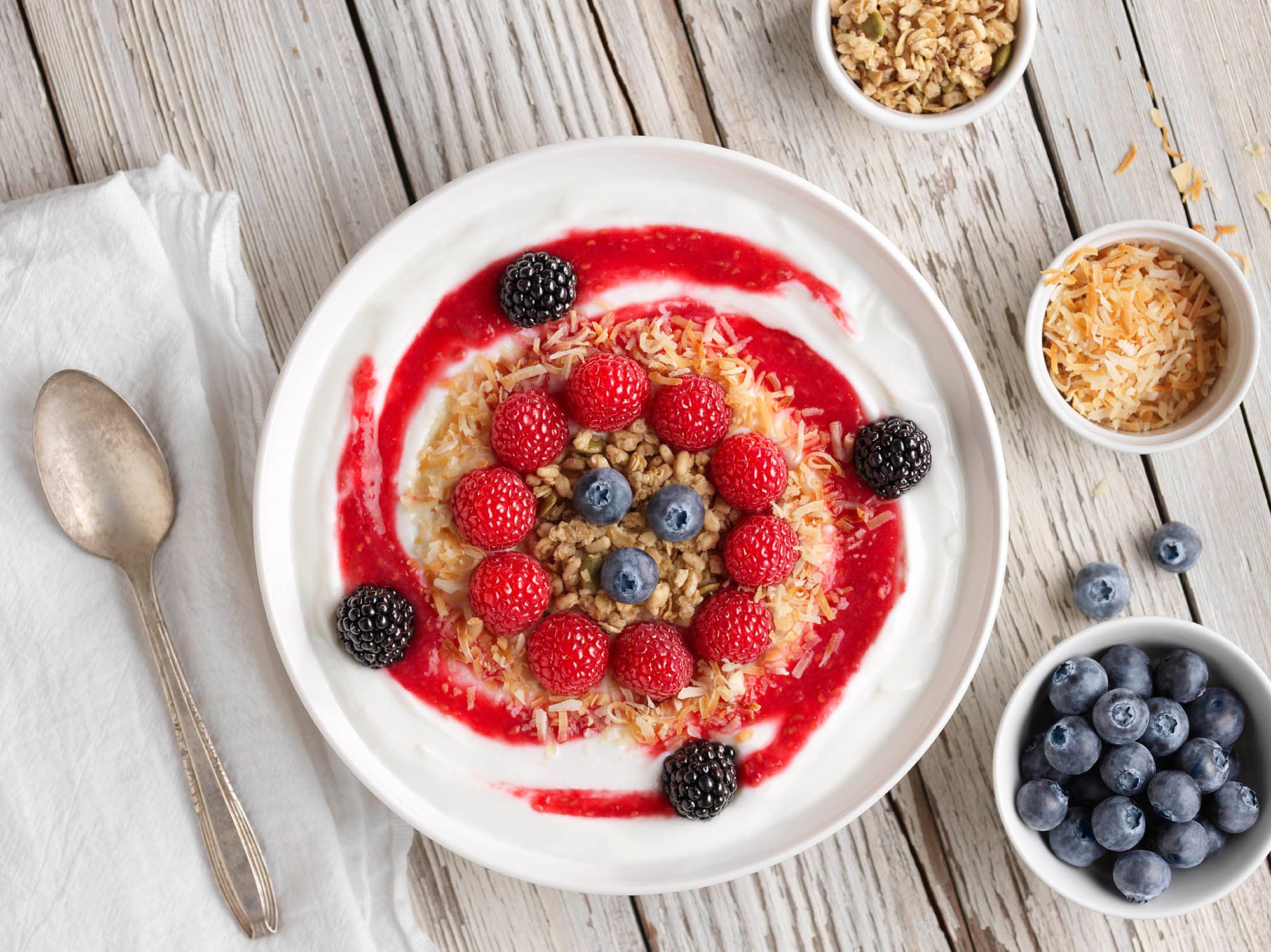 Raspberry smoothie bowl with decorative design and a bowl of blueberries