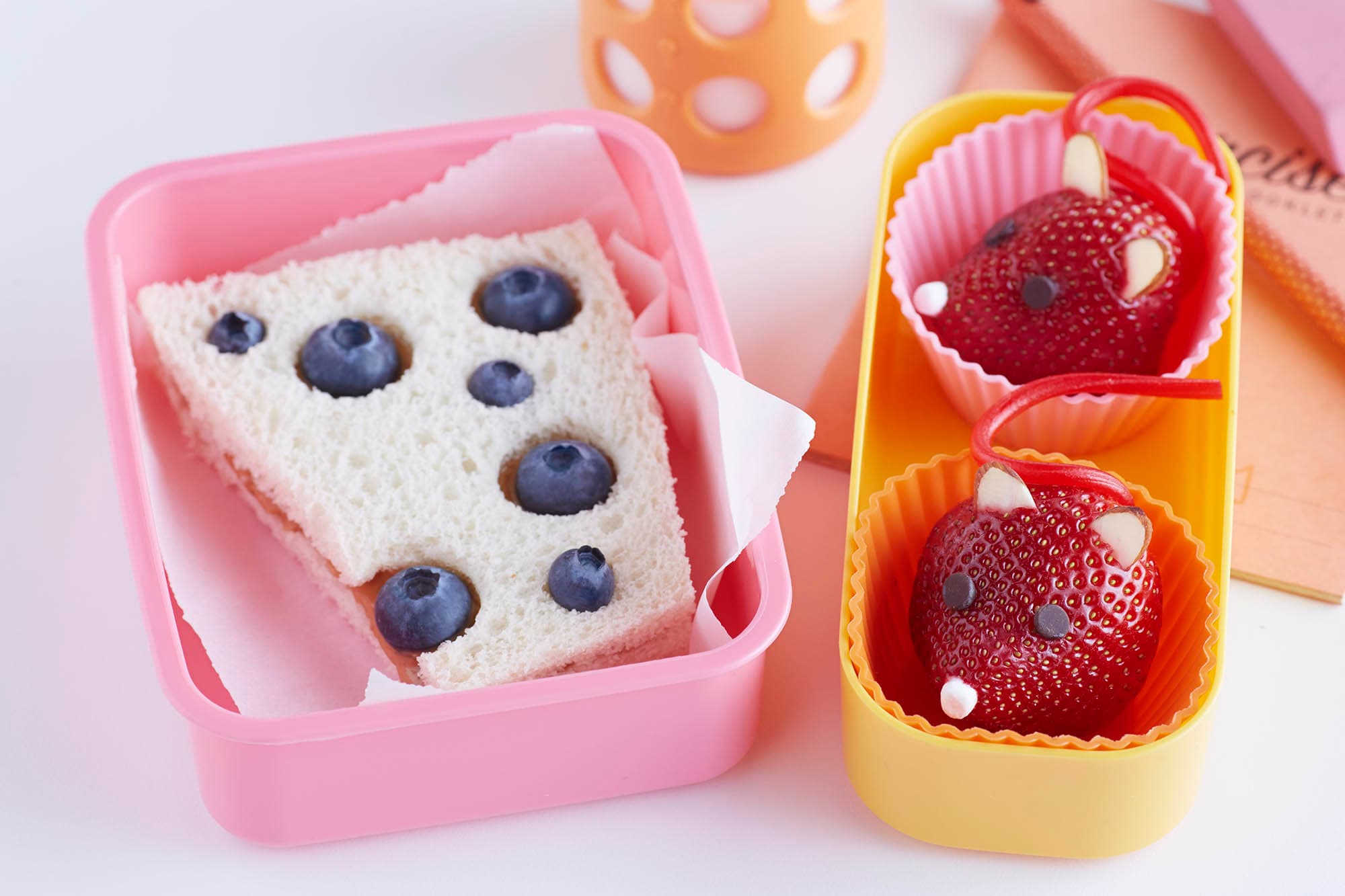 Bento box with fruit and a sandwich made to look like two mice and a slice of cheese