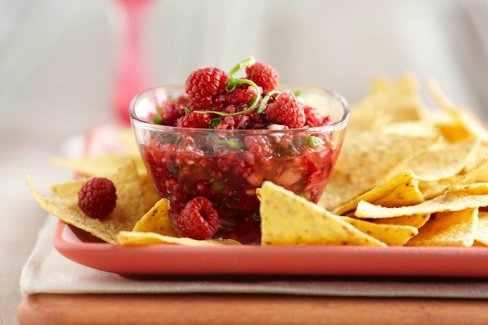 A cup of raspberry cilantro salsa surrounded by tortilla chips