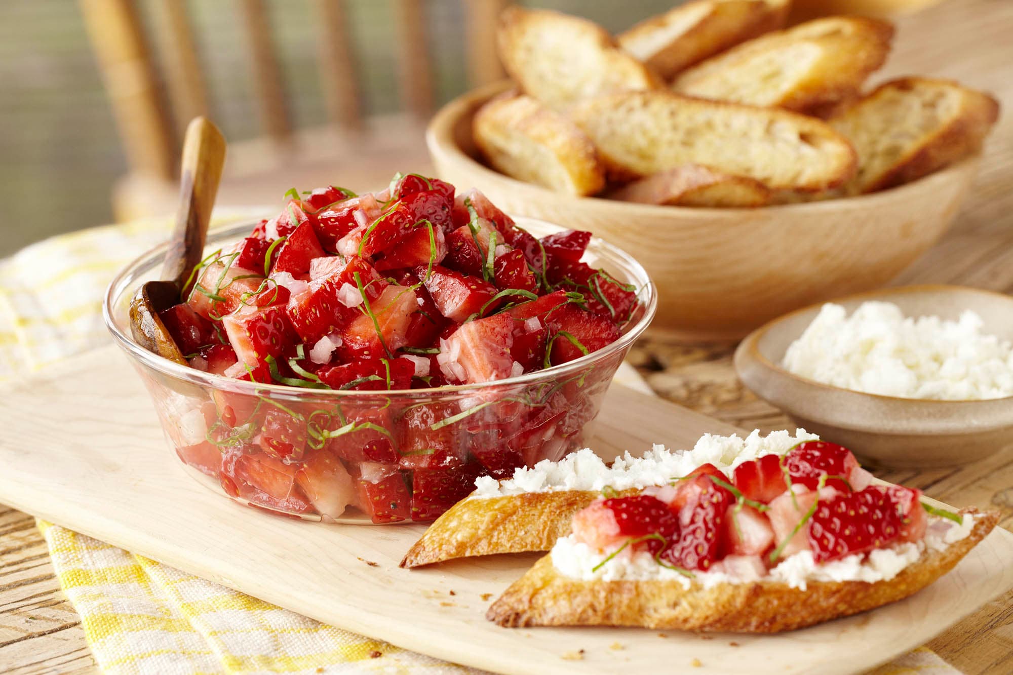 A bowl of strawberry basil salsa and a piece of toast with the salsa on top