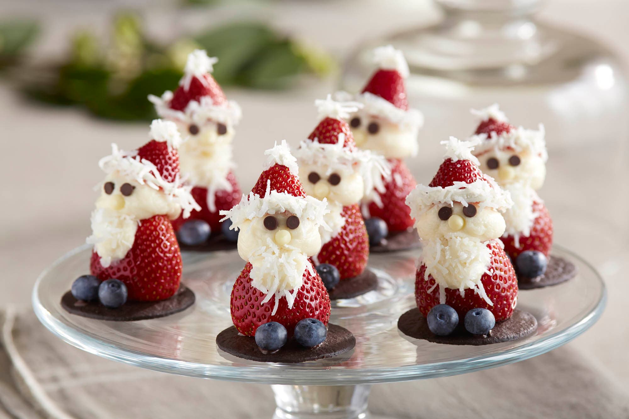Strawberries decorated to look like santas with coconut and blueberries