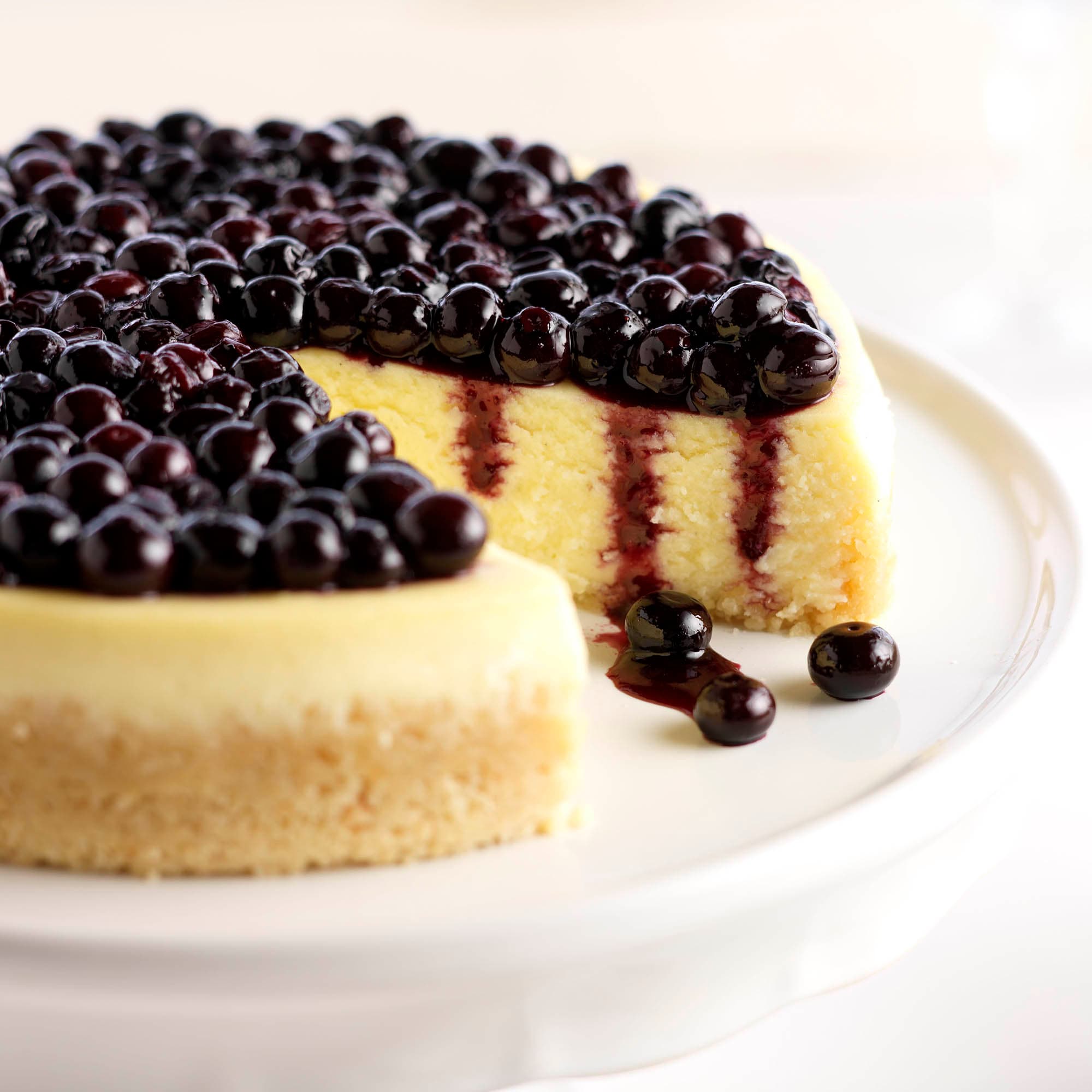 Platter with vanilla mascarpone blueberry cheesecake with a slice taken out of it