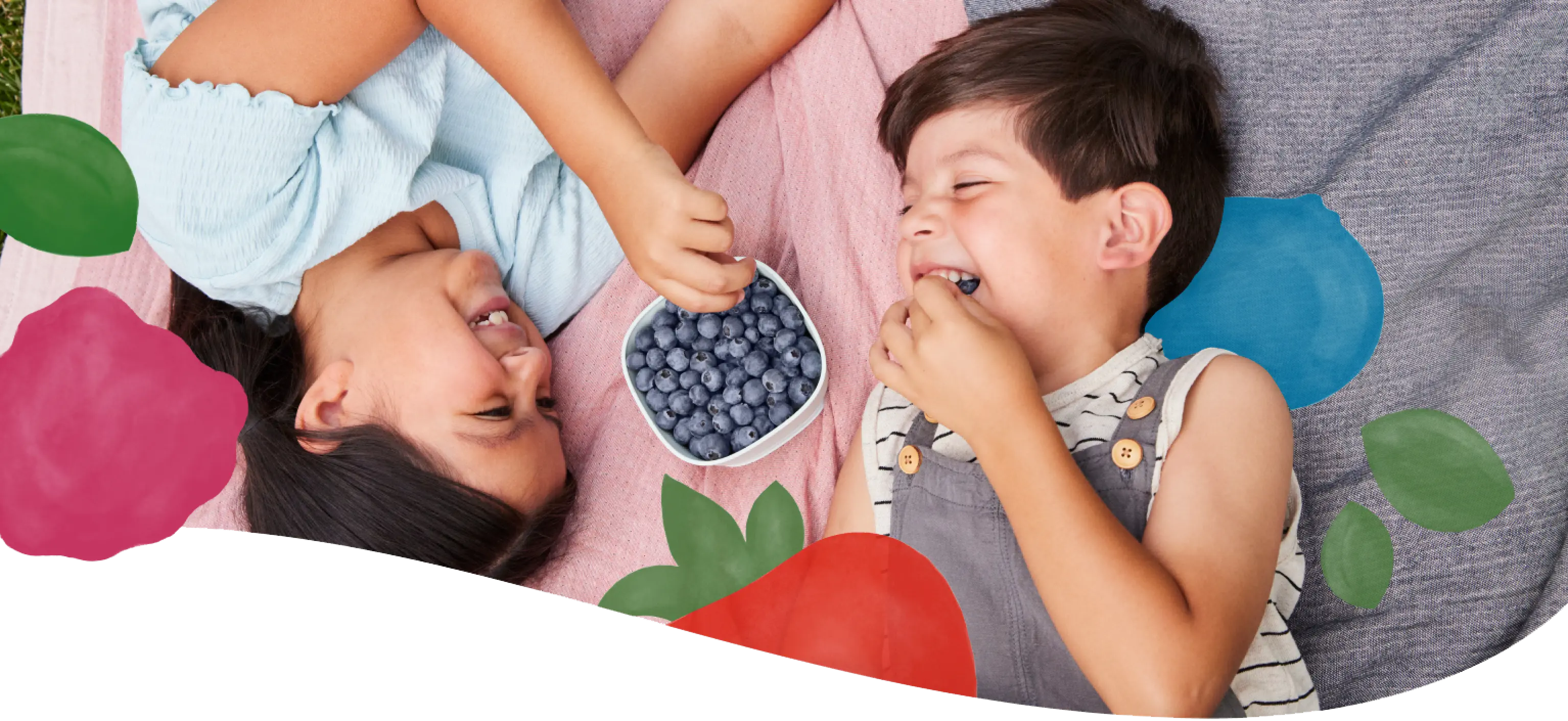 Kids sharing blueberries on a picnic blanket